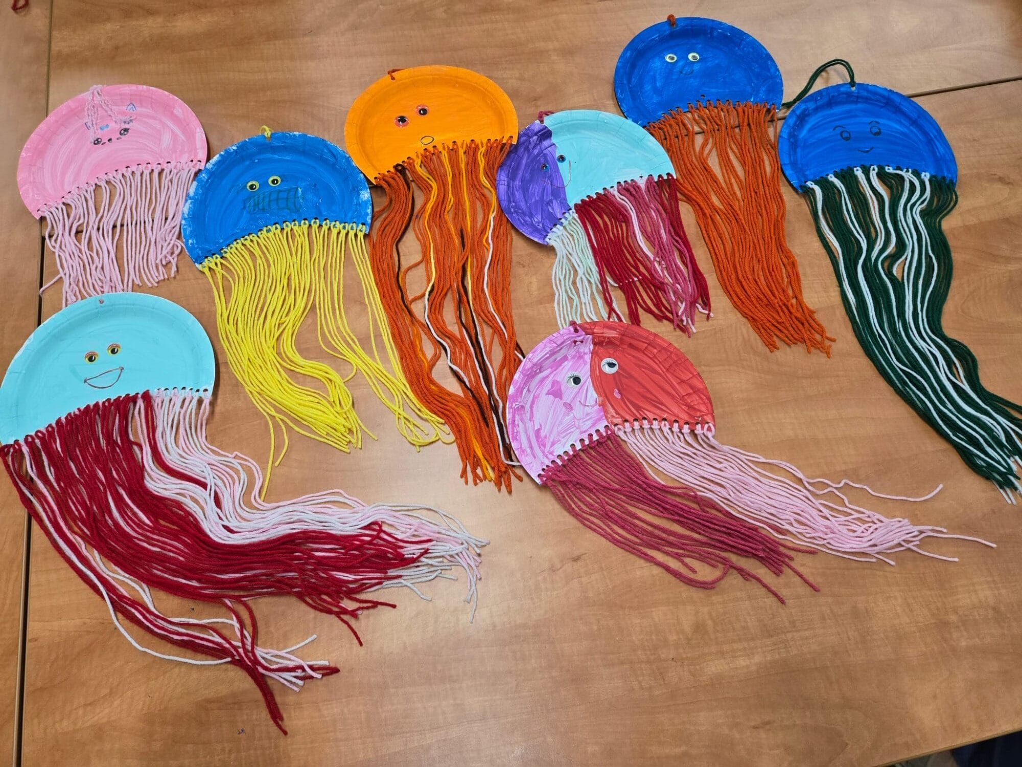 Colorful craft jellyfish made from paper plates and yarn.